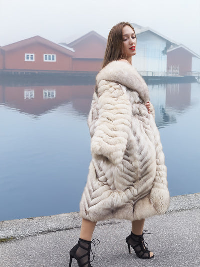 Luxurious blue fox fur coat with chevron design by waterfront.