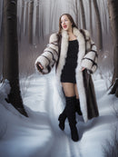 Woman in a fur coat standing in a snowy forest