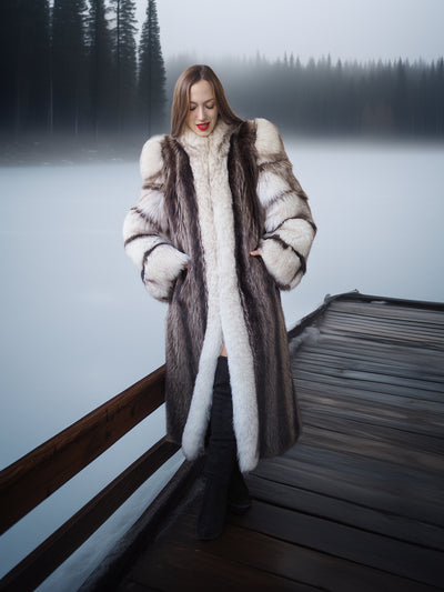 Woman in a fur coat standing on a dock by a lake with trees in the background