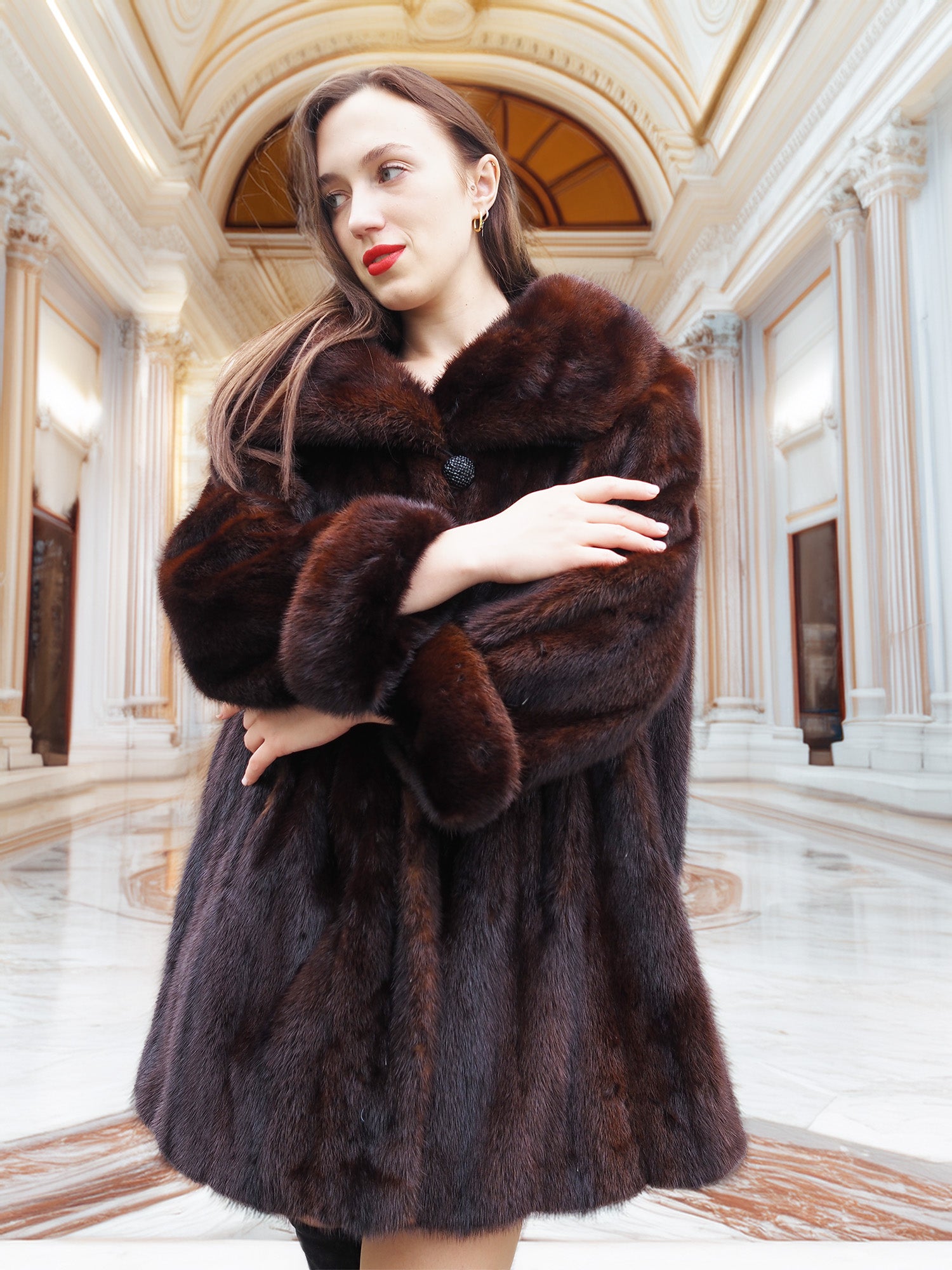 Model crossing arms in vintage mink coat, showcasing plush fur and timeless elegance in a marble hall.