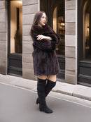 Mahogany mink coat styled with arms crossed, perfect for elegant winter outerwear in a neutral cityscape.