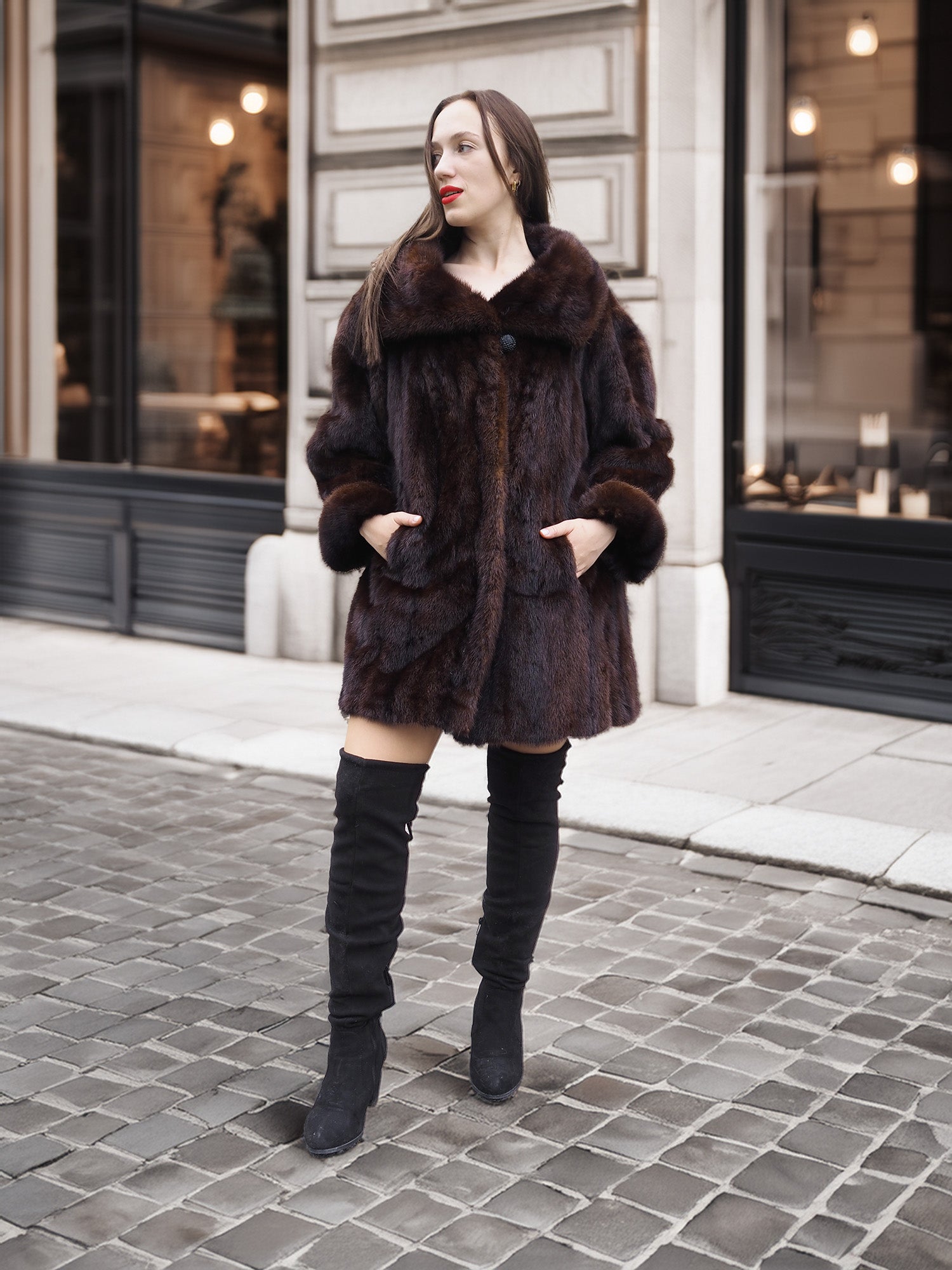 Model posing in vintage mink coat with hands in pockets, showcasing classic fur fashion on cobblestone streets.