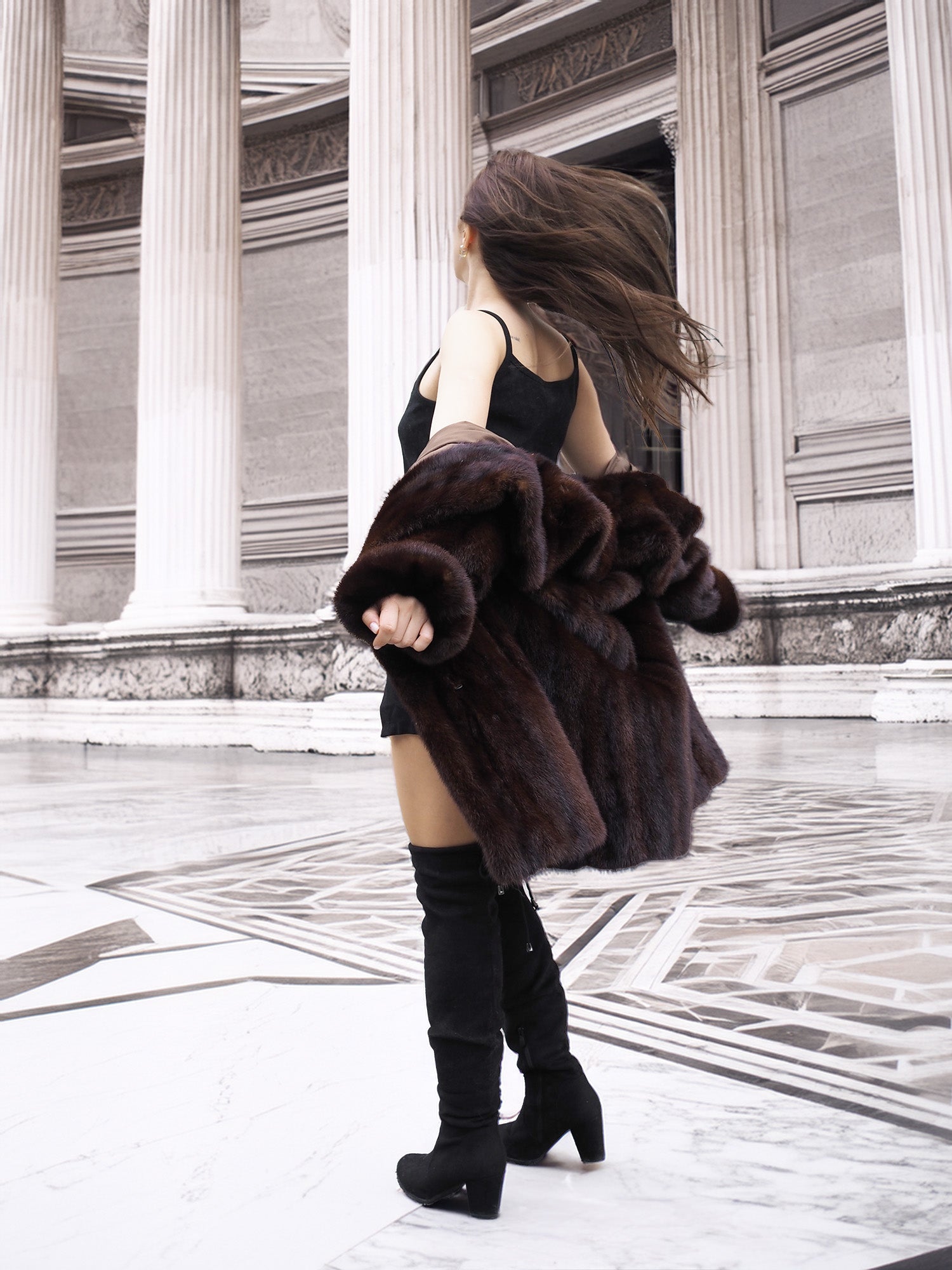 Model spinning in vintage mink coat, showcasing its movement and soft fur texture in a neoclassical architectural space.
