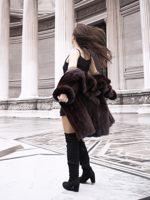 Model spinning in vintage mink coat, showcasing its movement and soft fur texture in a neoclassical architectural space.