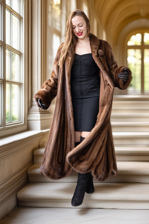 Brown mink fur coat with open front and long draped hem, standing pose
