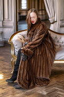 Brown mink fur coat with rounded cuffs and front clasp, worn while seated