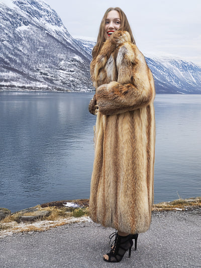 Woman in red fox coat by calm lake