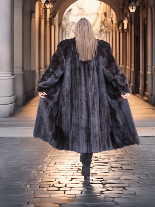 Back view of flowing Midnight Sonata black mink coat in motion, highlighting the coat’s dramatic volume and rich texture.