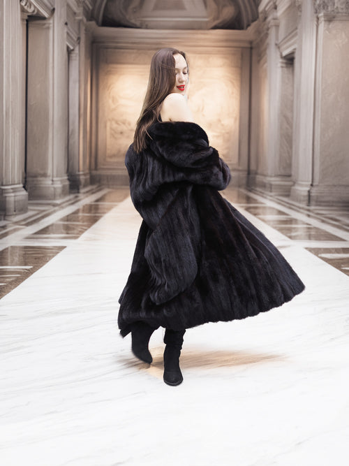 Woman spinning in Midnight Sonata black mink coat, revealing the coat’s luxurious fullness and graceful movement indoors.
