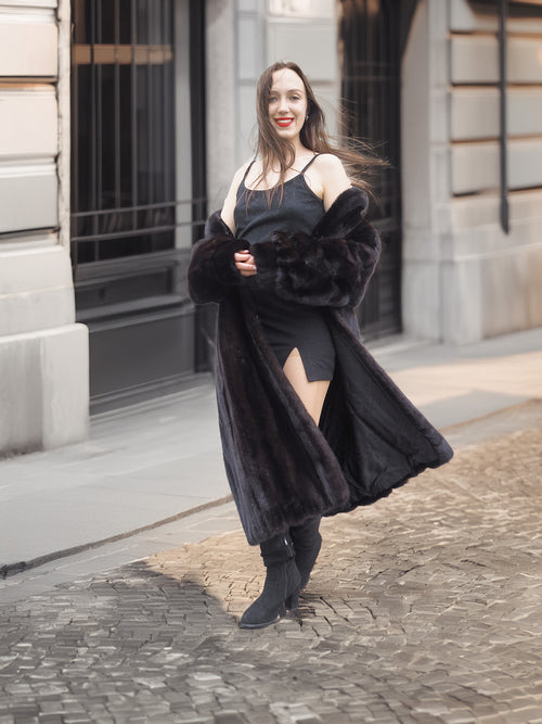Model smiling in Midnight Sonata black mink coat, styled with a black mini dress for a bold and elegant winter look.
