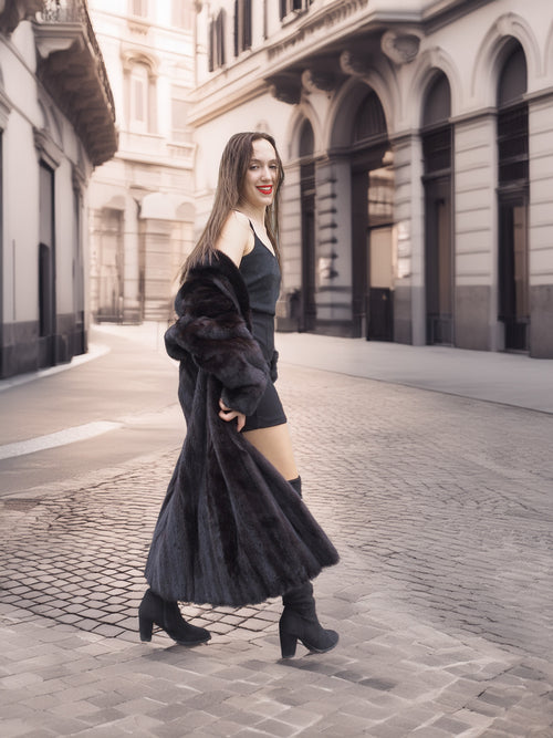 Woman walking in Midnight Sonata black mink coat, blending elegance and motion in a stylish city backdrop.