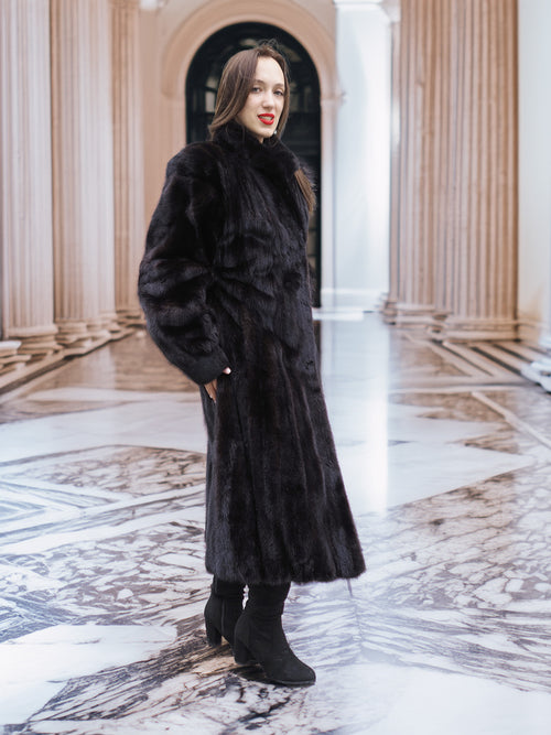 Midnight Sonata black mink coat displayed in a marble hall, highlighting its full-length design and refined fur texture.