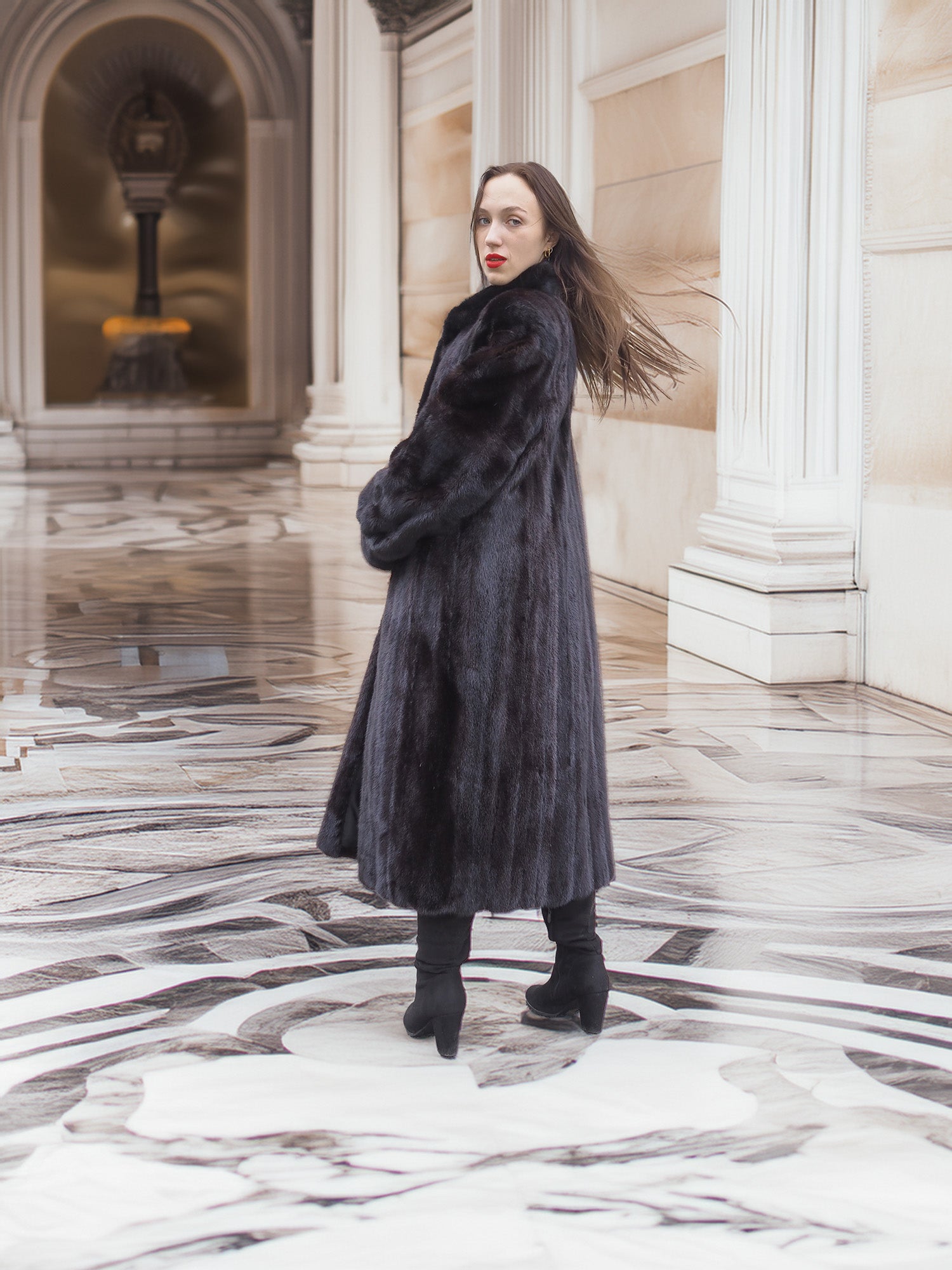 Model turning in Midnight Sonata black mink coat, showcasing its elegant drape and premium fur quality in a palace setting.