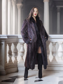 Woman wearing a long dark fur coat in an elegant interior setting