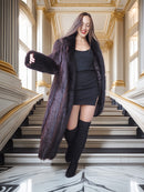 Woman in a long dark fur coat standing on a staircase in an elegant interior setting