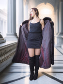 Woman holding a large purple coat in an elegant interior setting