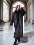 Woman wearing a long dark fur coat in an elegant hallway.