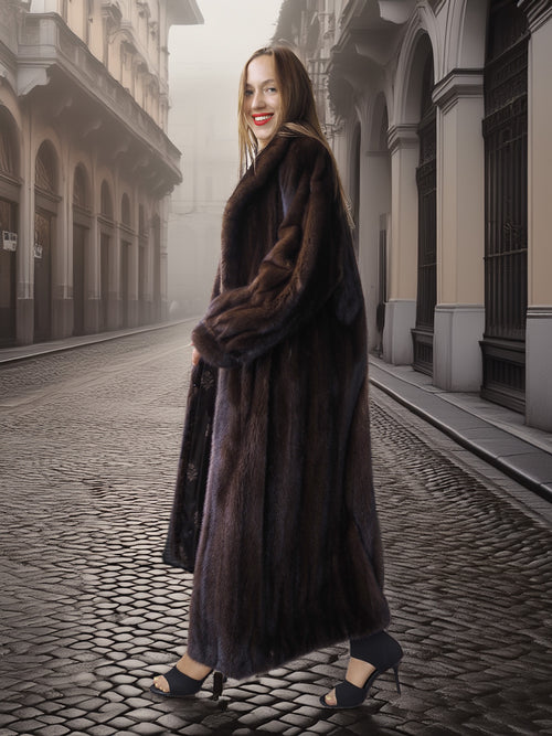 Woman in a long dark coat standing on a foggy street with old buildings.