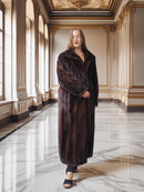 Woman wearing a long brown fur coat in an elegant interior setting