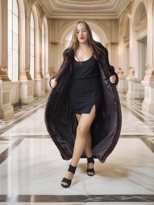 Woman in a long dark coat and black dress standing in an elegant interior setting