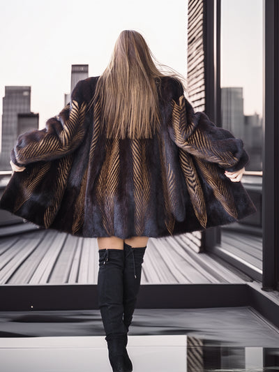 Person wearing a patterned coat and black boots standing on a rooftop with cityscape view.