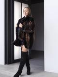Woman wearing a dark fur coat and black knee-high boots in a minimalistic setting.