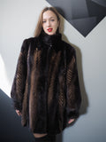 Woman wearing a dark fur coat with geometric wall background