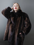 Woman wearing a dark fur coat with a patterned design against a gray background