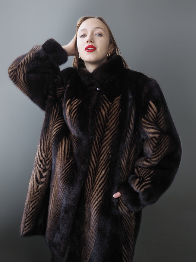 Woman wearing a dark fur coat with a patterned design against a gray background