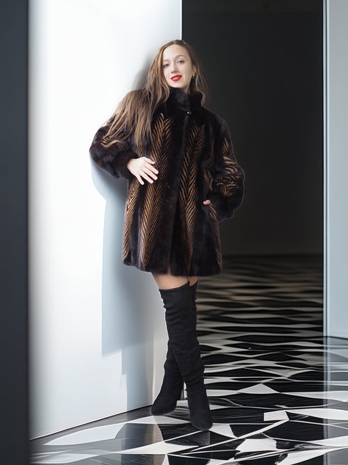 Woman in a fur coat and knee-high boots standing against a black and white checkered floor.
