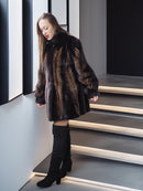 Woman wearing a fur coat and black boots on a modern staircase.