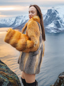 Red and gray fox fur coat by The Wild Muse, worn on a mountain ledge at sunset, showcasing its rich texture and natural fur elegance.