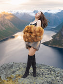 The Wild Muse luxury fur coat in red and gray fox, styled with joy and movement atop a scenic cliff for a bold fashion statement.