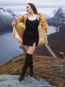 The Wild Muse fox fur coat in red and gray tones, opened to reveal inner lining, styled in a cinematic mountain backdrop.