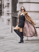 Model leans against a wall in Harlow pastel mink coat, revealing its silky interior and stylish vintage appeal.