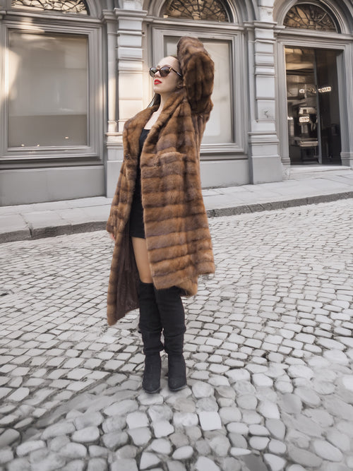 Model poses confidently in Harlow pastel mink coat with shawl collar, styled with a black mini dress and knee-high boots.