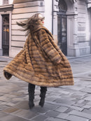 Harlow - Pastel Mink Shawl Collar vintage coat in horizontal striped mink fur, flaring elegantly while walking on cobblestone streets.