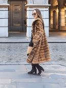 Side view of Harlow pastel mink shawl collar coat in motion, styled with black mini dress and heeled boots for a modern vintage look.