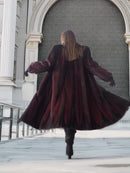 Back view of flowing two tone mink fur coat in red and black, showcasing full-length design and dramatic movement.