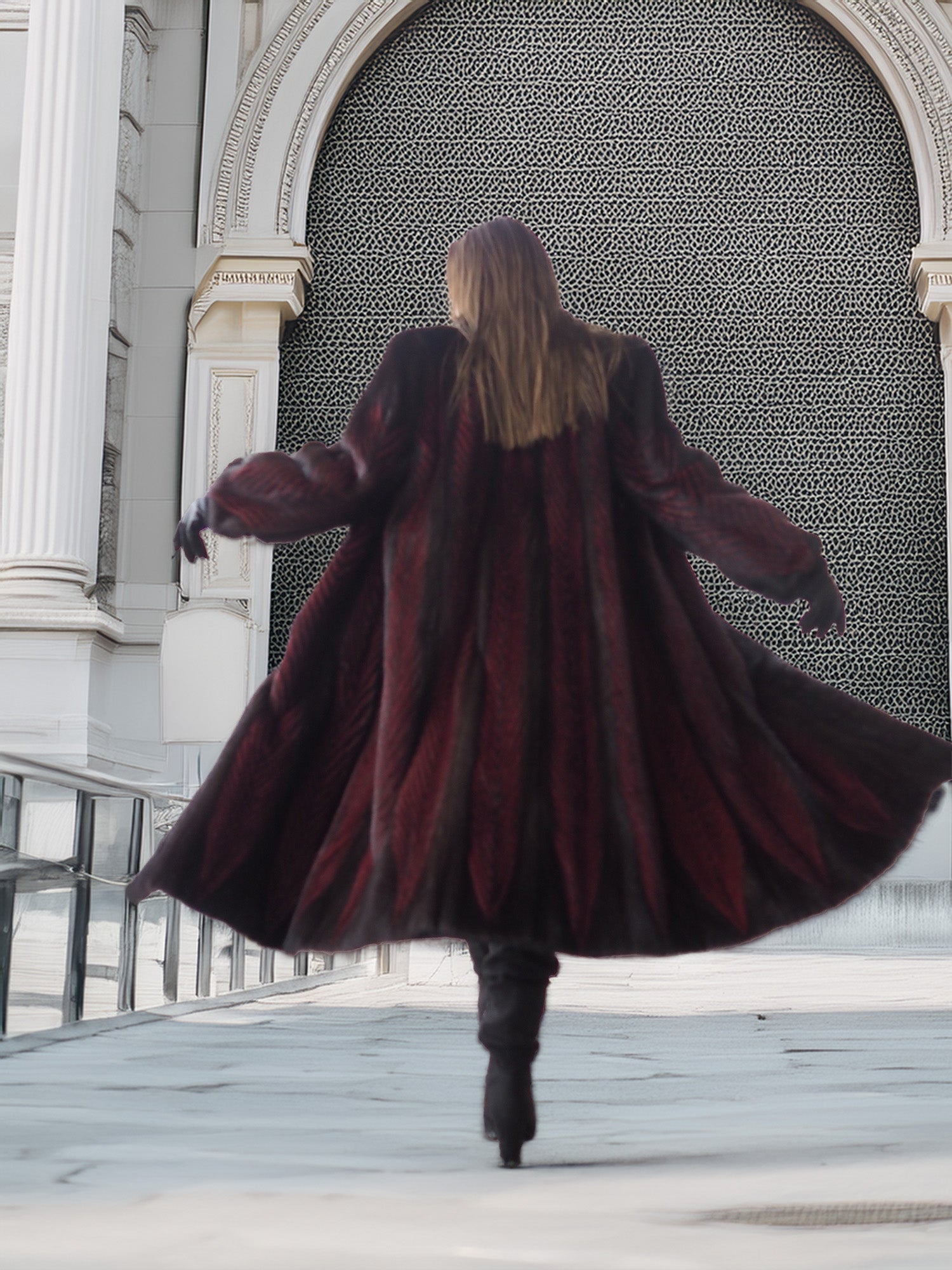 Back view of flowing two tone mink fur coat in red and black, showcasing full-length design and dramatic movement.