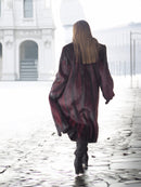 Back view of red and black mink fur coat in motion, emphasizing its full-length cut and dramatic winter style.