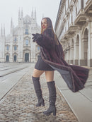 Model twirls in red and black mink fur coat near cathedral, combining classic architecture with elegant fur fashion.