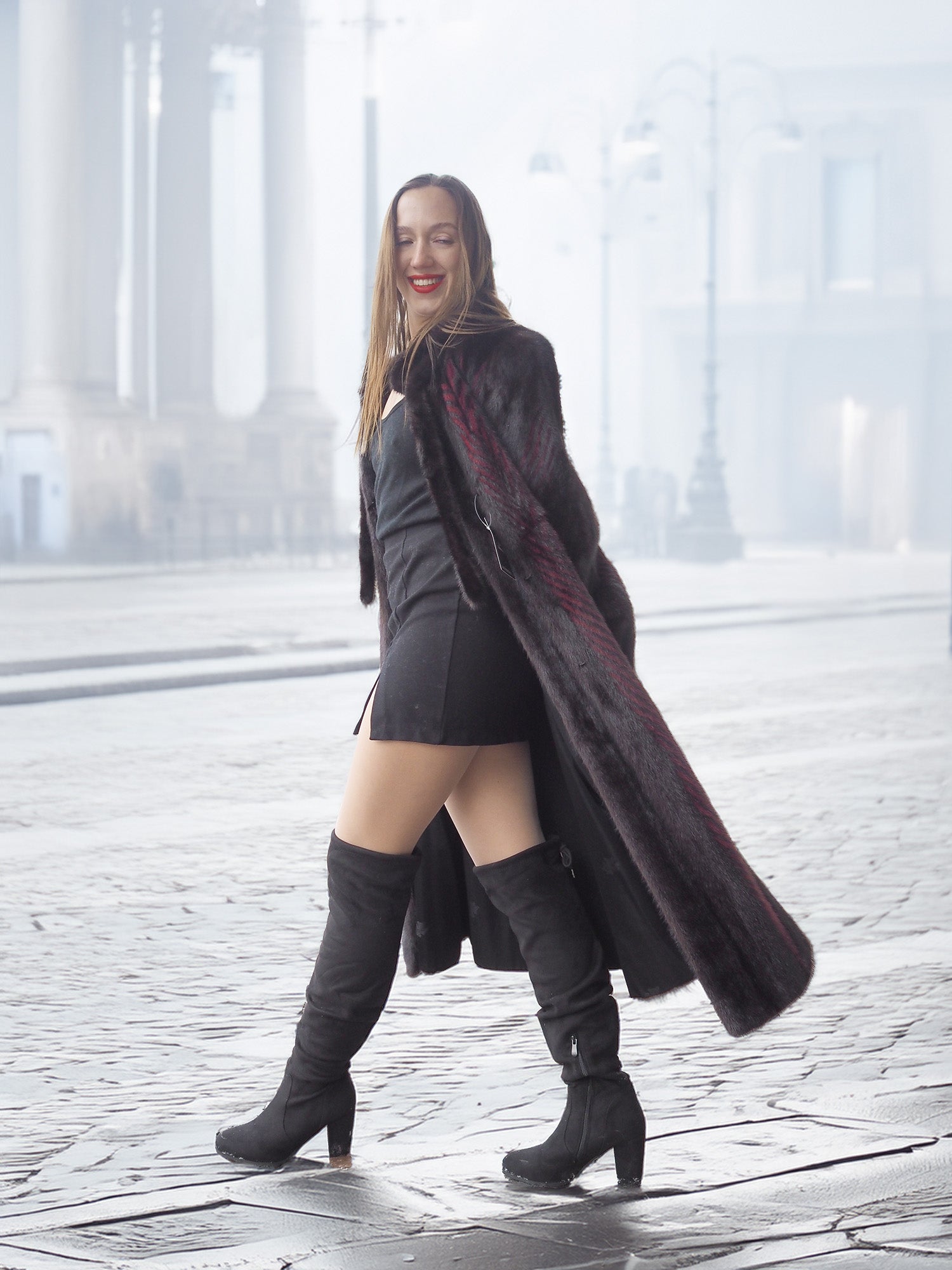 Model walks confidently in red and black mink fur coat and black boots, perfect for luxury winter street style.