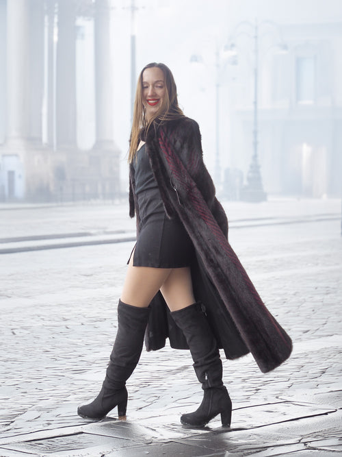 Model walks confidently in red and black mink fur coat and black boots, perfect for luxury winter street style.