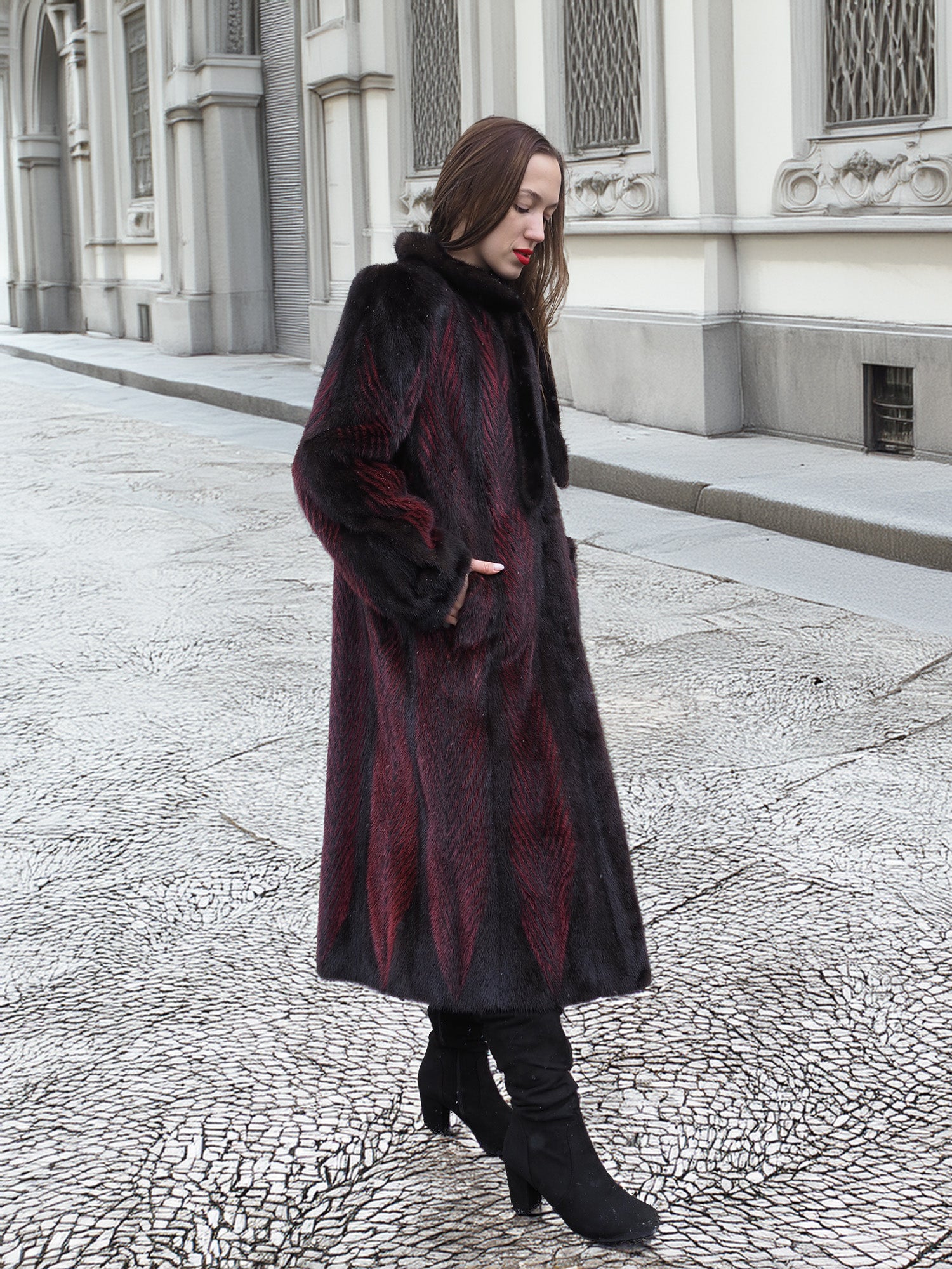 Model walks along textured pavement in red and black mink fur coat, highlighting its elegant and sustainable design.