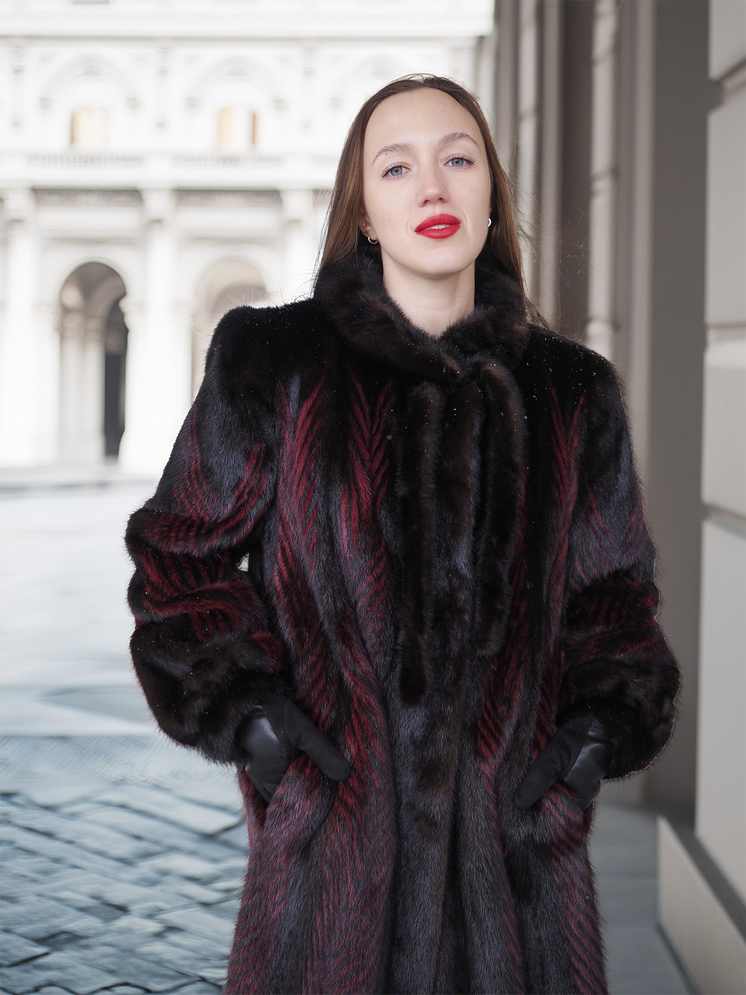 Close-up of model in red and black mink fur coat with fur collar and gloves, showcasing refined winter elegance.