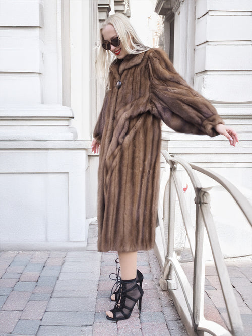 Vintage Canadian brown mink fur coat with silk lining, showcased in a dramatic pose on a city street.