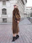 Elegant woman in long brown mink fur coat and high heels posing on city street.