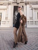 Elegant woman in vintage pastel Canadian brown mink fur coat and sunglasses posing outdoors against ornate building facade.