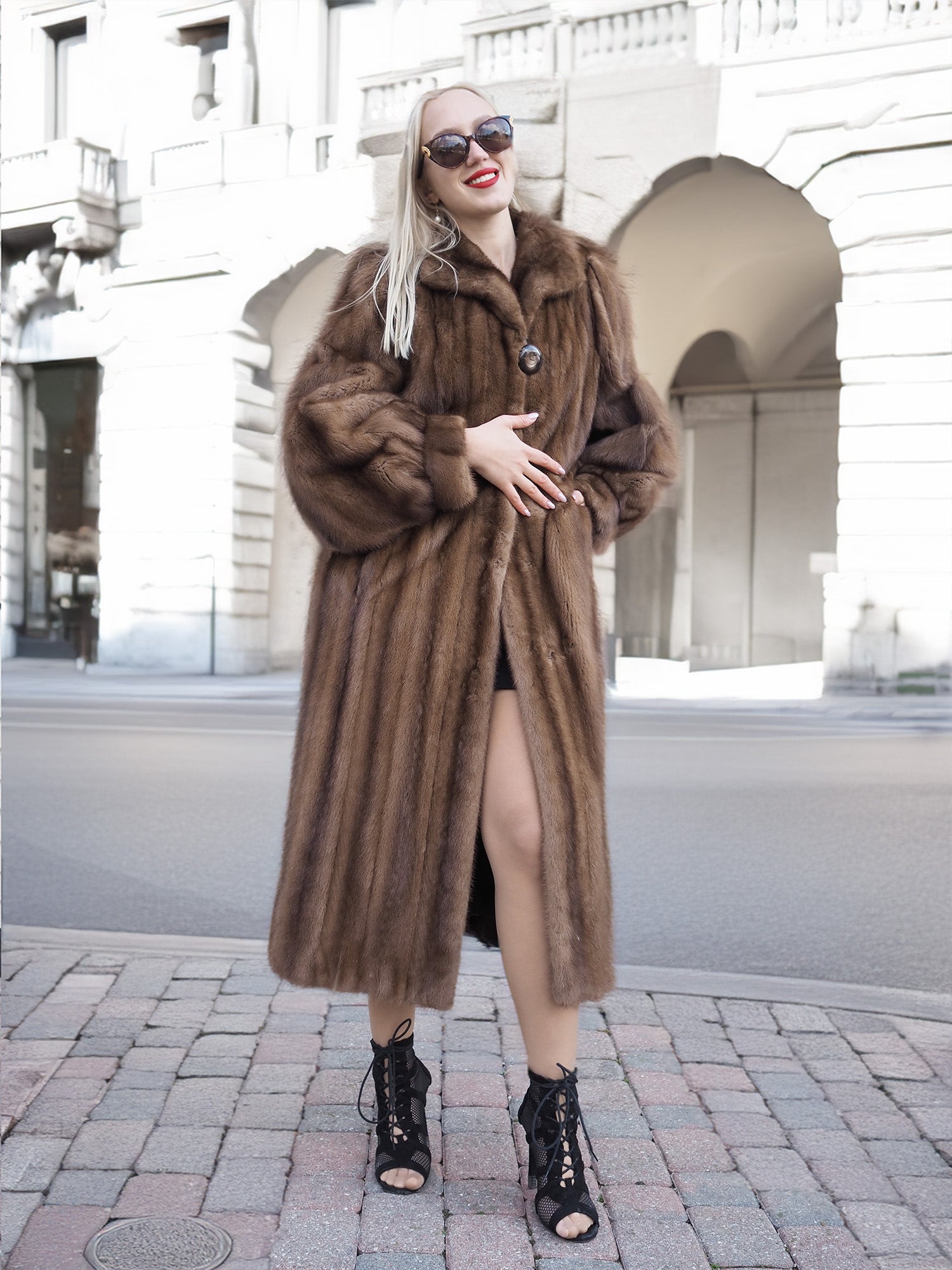 Elegant brown mink fur coat with silk lining, worn by a woman standing in front of a historic building